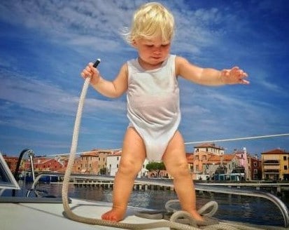 enfant blond à bord d'un bateau collier Pellestrina Venise